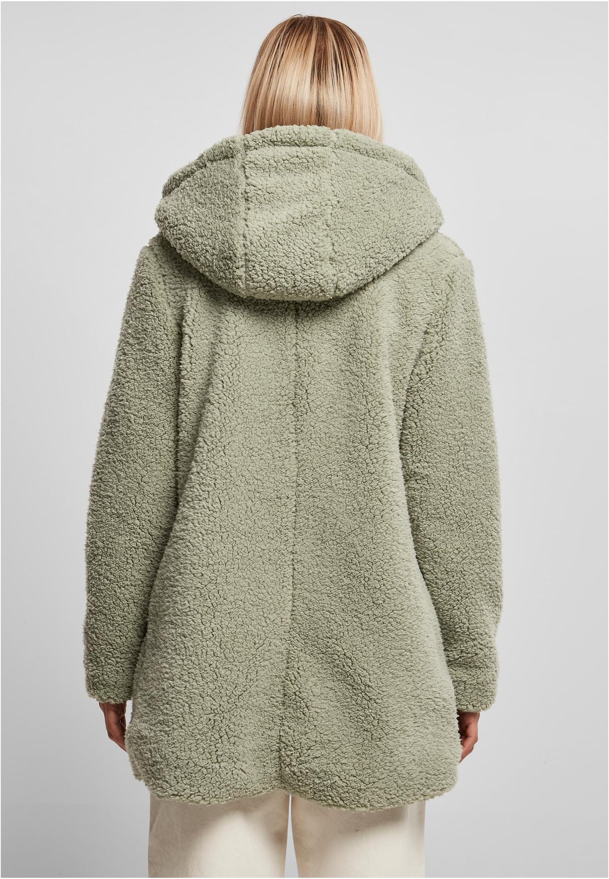 En kvinna visar baksidan av den gröna UC Sherpa Jacket.