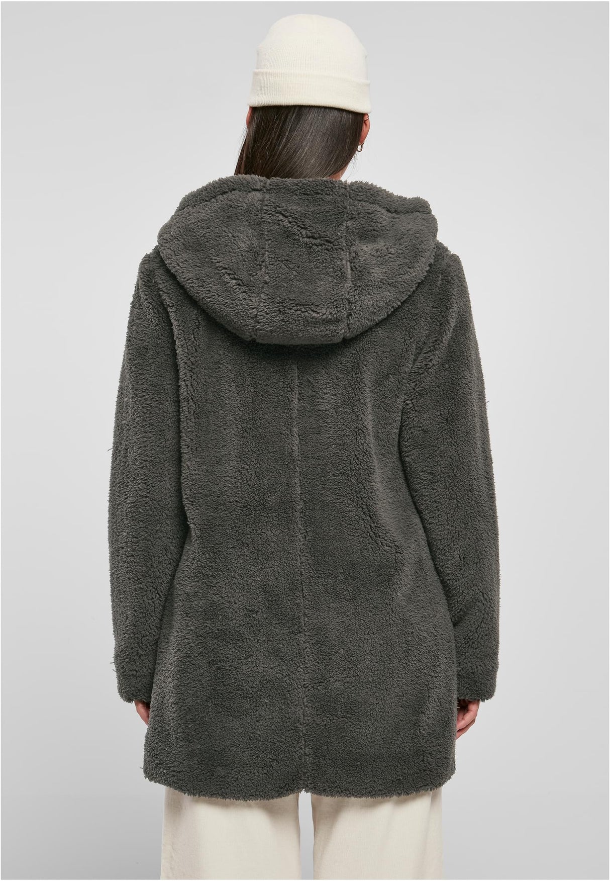 En kvinna, sedd bakifrån, som bär en mörkgrå och fluffig sherpajacka med huva.