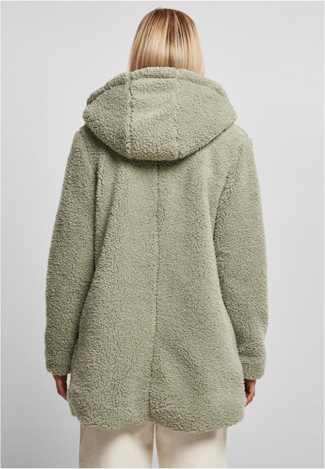 En kvinna visar baksidan av den gröna UC Sherpa Jacket.