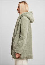 En kvinna i profil som bär en grön, luddig sherpajacka med huva.